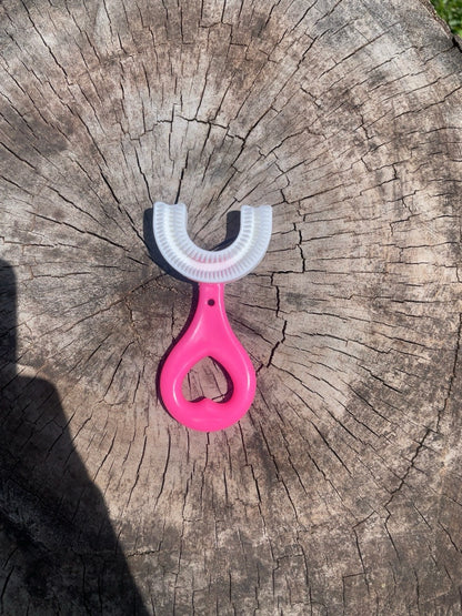 Fotografía original del cepillo manual infantil en U rosado con mango de abertura en corazón